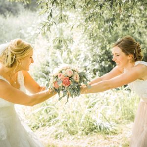 hochzeitsshooting braut und trauzeugin ziehen am brautstrauss in burgebrach