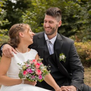 lachendes ehepaar am hochzeitstag in der natur bei hochzeitsshooting