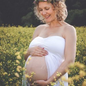 schwangere mit blumenkranz im rapsfeld in hirschaid bei babybauchshooting