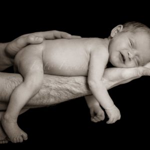 lachendes baby auf unterarm des vaters bei neugeborenenshooting zuhause in adelsdorf raum erlangen-hoechstadt